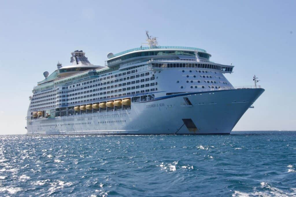 A large white cruise ship sails on calm blue water under a clear sky, offering comfort and style for guests embarking on memorable Edinburgh Shore Excursions in Scotland.