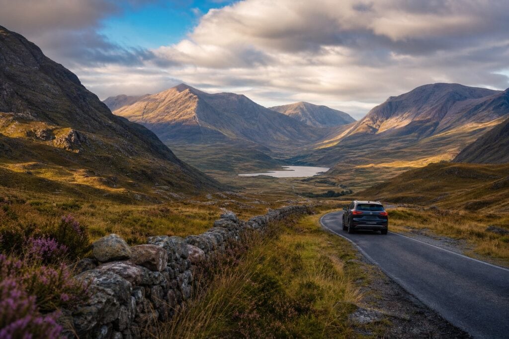 Car driving on a scenic single-track road through the Scottish Highlands